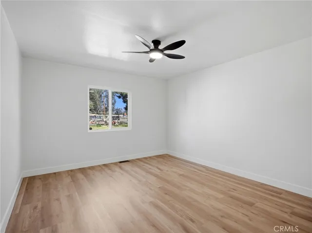 an empty room with wooden floor ceiling fan and windows