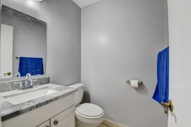 a bathroom with a granite countertop sink toilet and a mirror