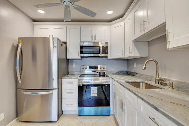 a kitchen with stainless steel appliances granite countertop a refrigerator a stove a sink and a microwave