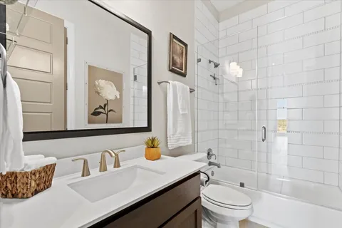 a bathroom with a bathtub shower sink vanity mirror and toilet