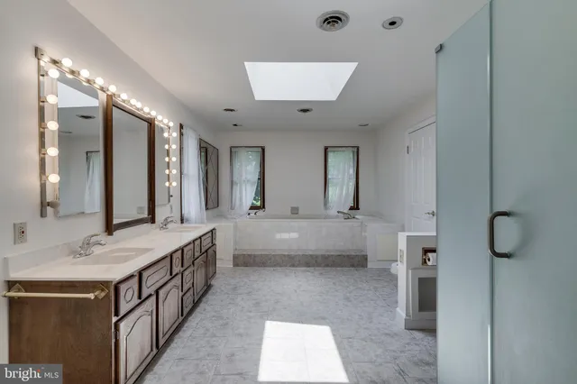 a bathroom with a double vanity sink and mirror with bathtub