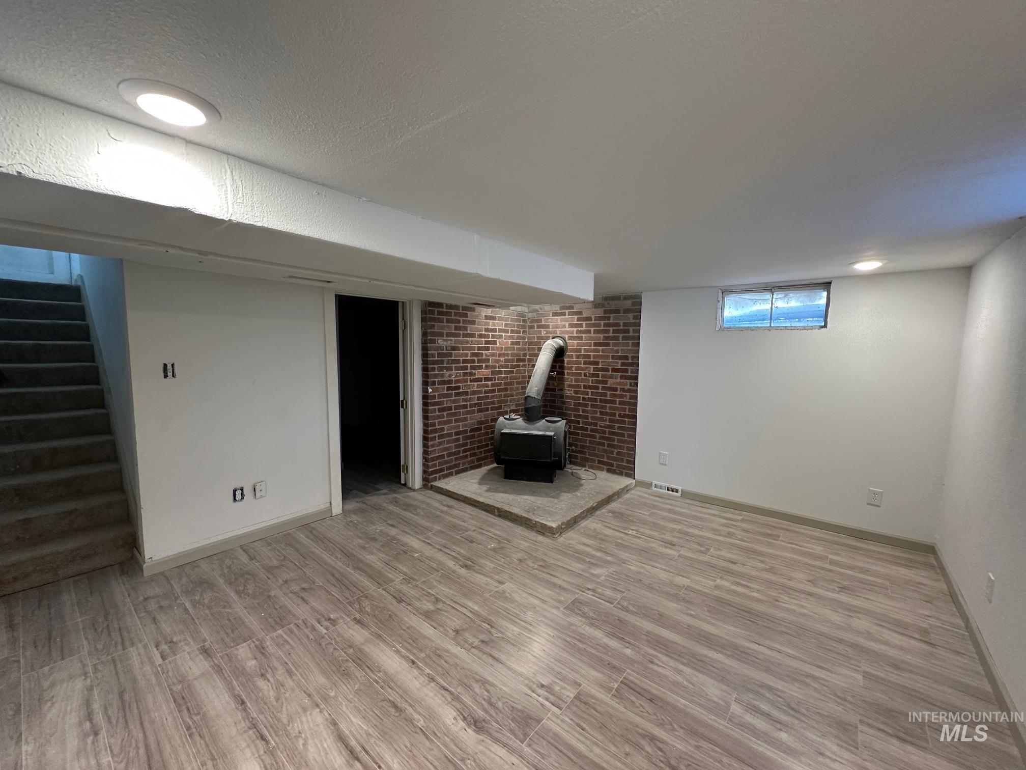 264 Southwest 10th Avenue Ontario, OR 97914 - Photo 16 of 26 Below grade area featuring a wood stove, light wood finished floors, stairs, and a textured ceiling