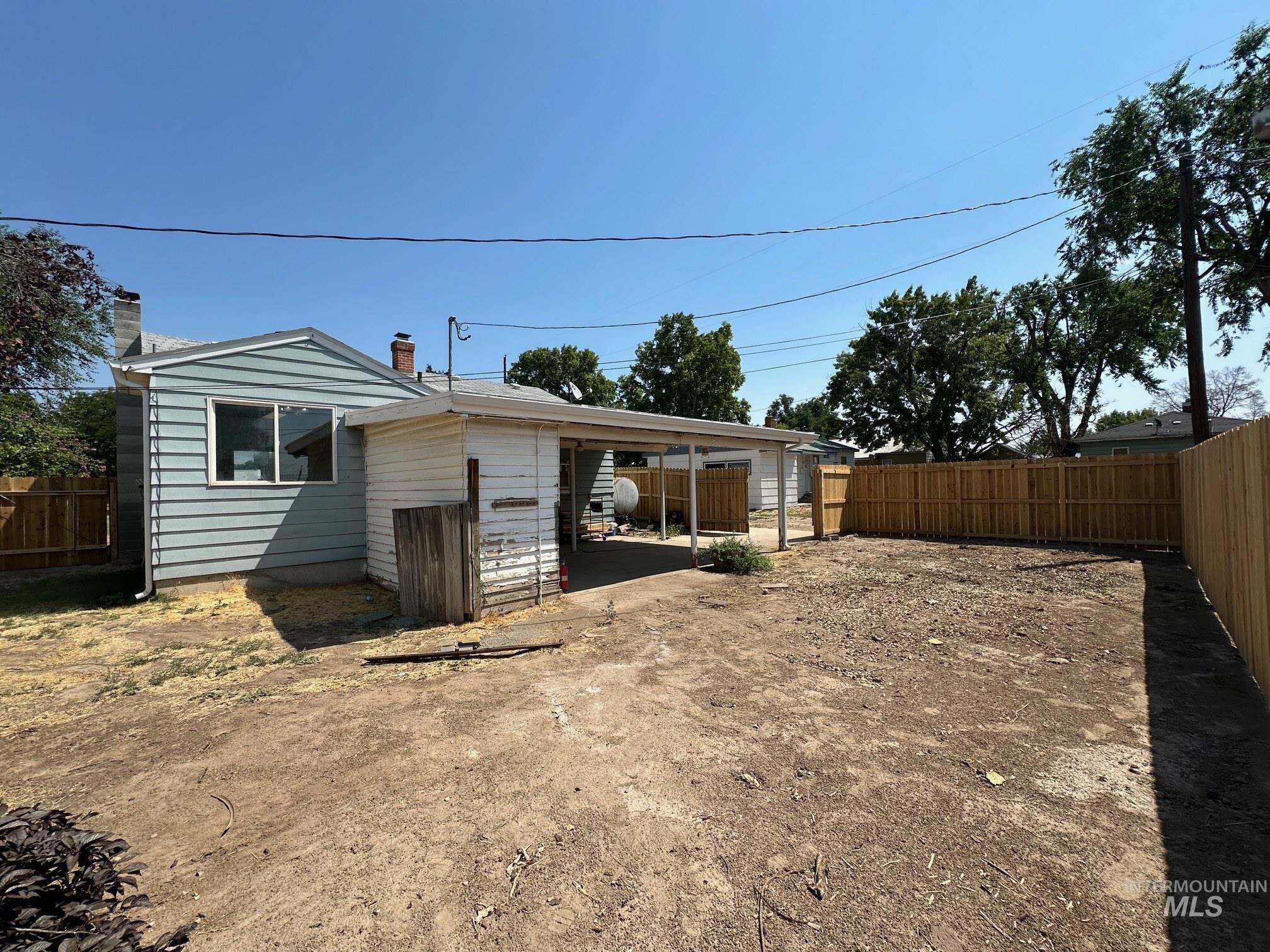 264 Southwest 10th Avenue Ontario, OR 97914 - Photo 20 of 26 Back of property with a fenced backyard, a carport, and a chimney