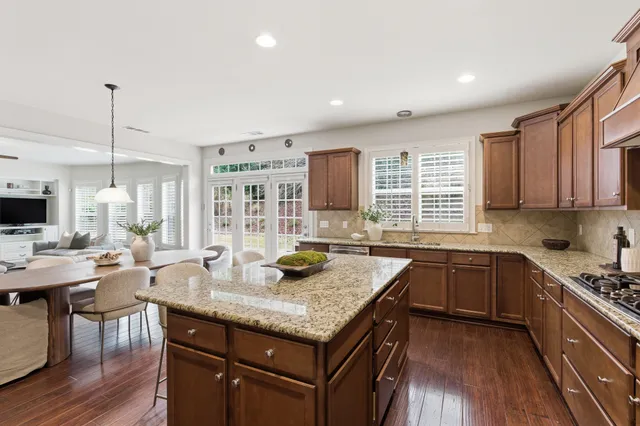 a kitchen with granite countertop kitchen island stainless steel appliances a sink stove and cabinets