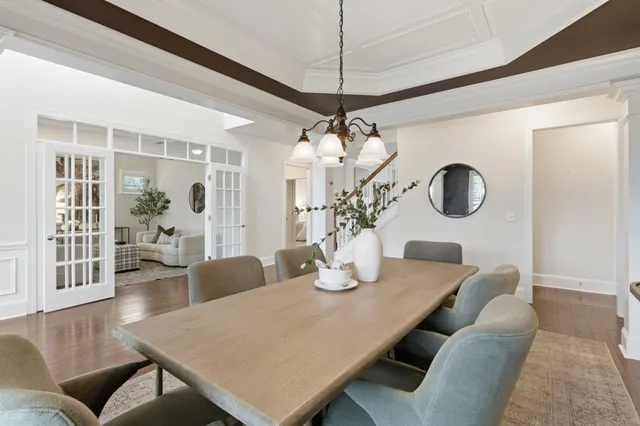 a dining room with wooden floor a chandelier a wooden table and chairs