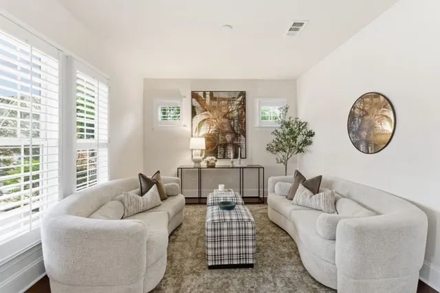 a living room with furniture a large window and a potted plant