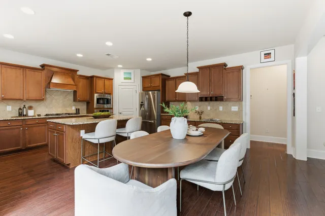 a kitchen with stainless steel appliances kitchen island granite countertop a sink a stove a dining table and chairs