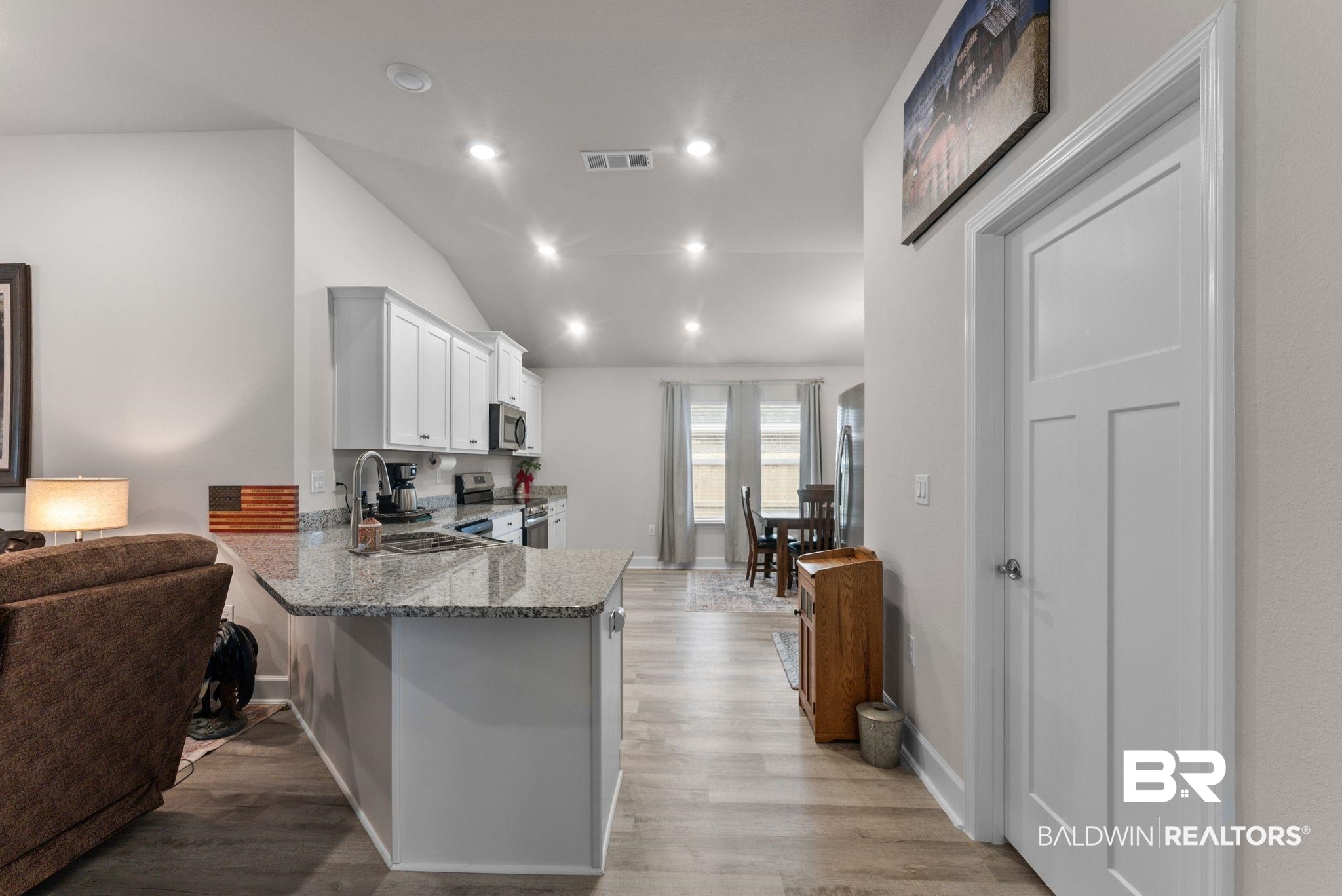692 Mayflower Drive Foley, AL 36535 - Photo 12 of 40 Kitchen featuring a peninsula, light stone counters, stainless steel appliances, white cabinetry, and light wood finished floors