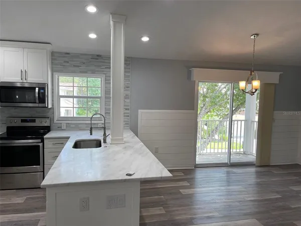 a kitchen with kitchen island granite countertop a stove and a wooden floor