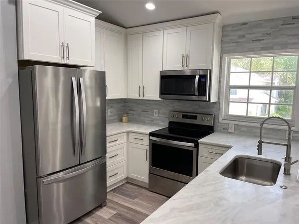 a kitchen with granite countertop a refrigerator and a sink
