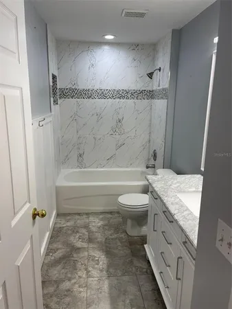 a bathroom with a granite countertop toilet sink and mirror
