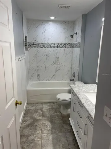 a bathroom with a granite countertop toilet sink and mirror