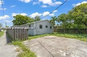 a backyard of a house with plants and tree with wooden fence