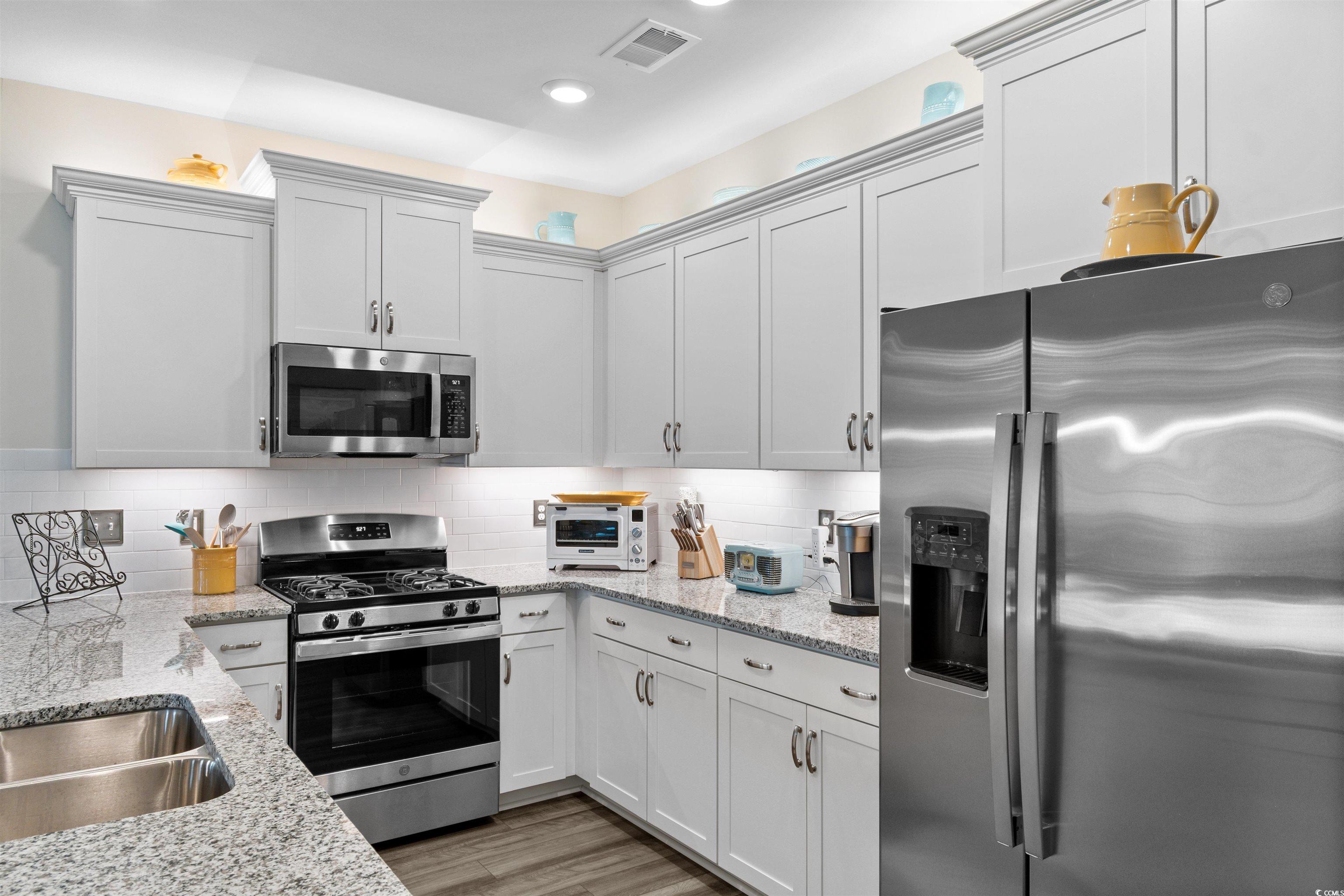 240 Sundew Loop Little River, SC 29566 - Photo 6 of 40 Kitchen with stainless steel appliances, tasteful backsplash, light stone countertops, light wood finished floors, and recessed lighting