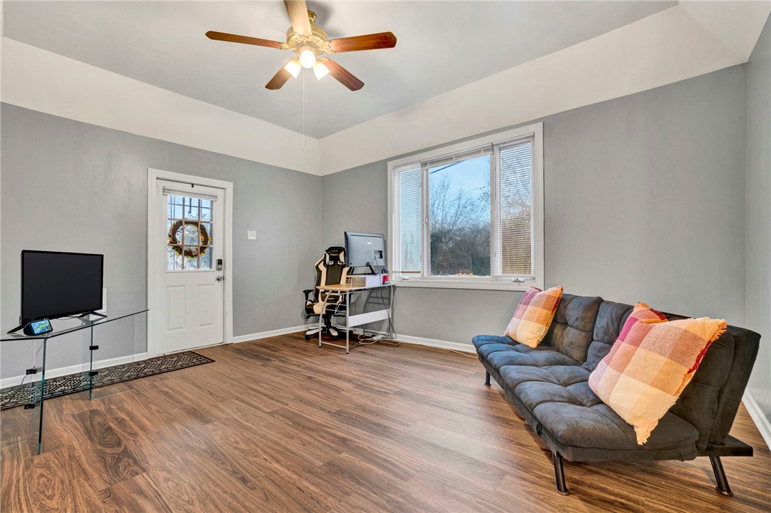 2505 East Brown Street Seneca, SC 29678 - Photo 12 of 43 This living room features rich wood flooring, a ceiling fan, and large windows inviting abundant light.