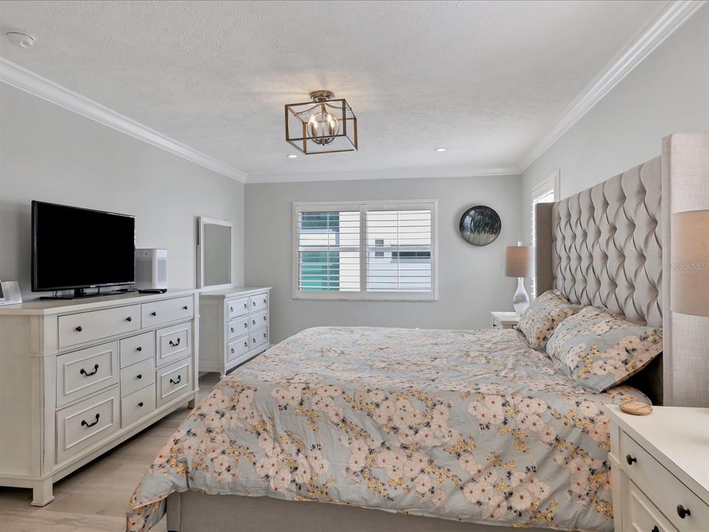 226 Golden Gate Point, Unit 44 Sarasota, FL 34236 - Photo 37 of 65 a bedroom with a large bed and a flat screen tv