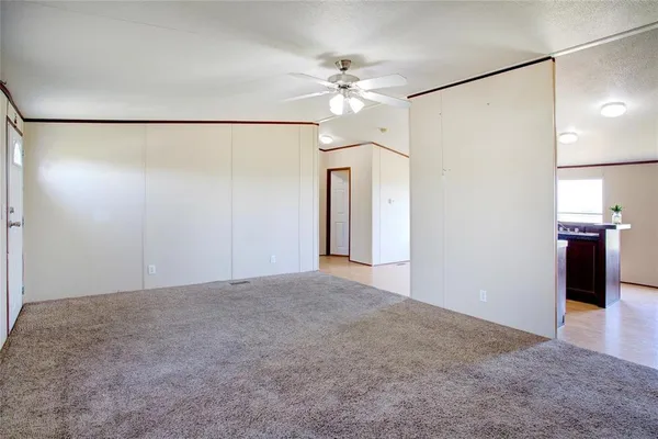 a view of a big room with a chandelier fan and windows