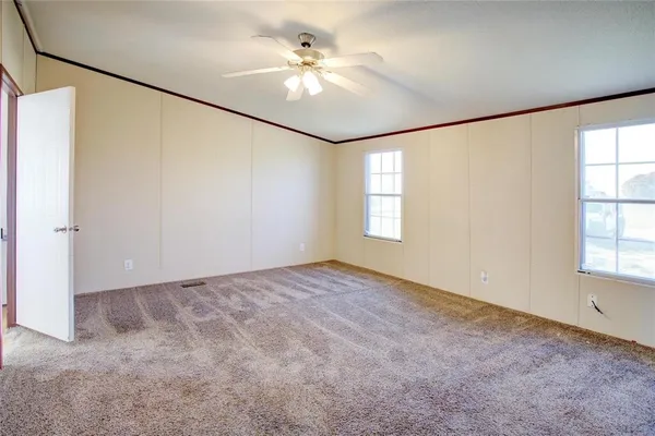 an empty room with windows and ceiling fan