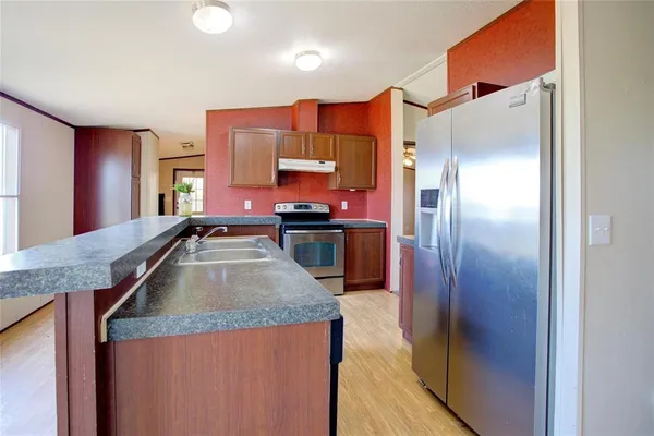 a kitchen with stainless steel appliances granite countertop a refrigerator a stove and a sink