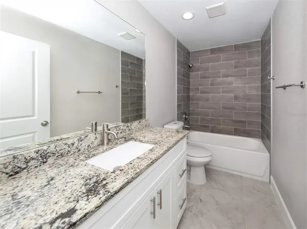 a bathroom with a granite countertop sink a toilet and bathtub