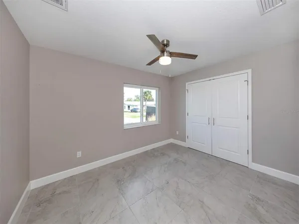 an empty room with a window and a ceiling fan