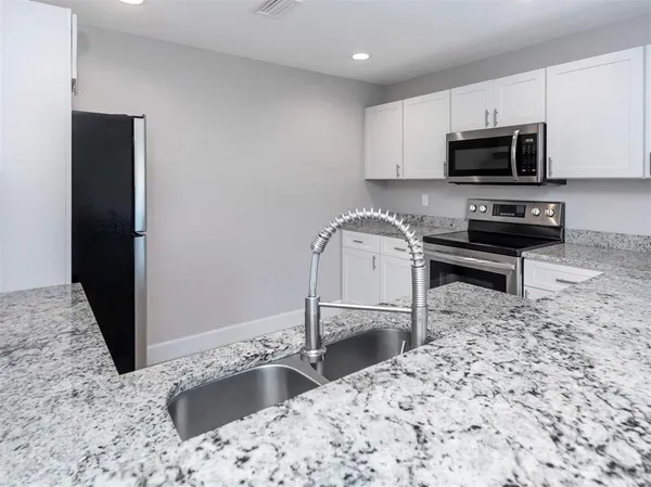 a kitchen with granite countertop a sink and a stove top oven