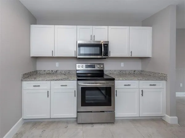 a kitchen with granite countertop white cabinets and stainless steel appliances