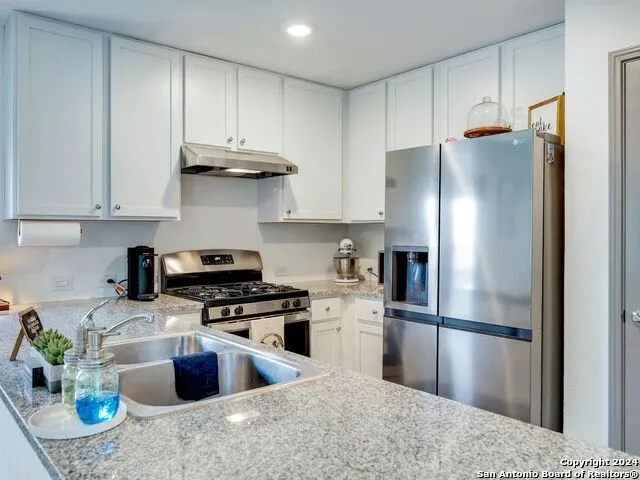 a kitchen with stainless steel appliances granite countertop a refrigerator a stove a sink a microwave and dining table