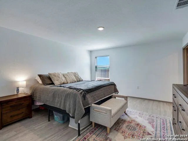 a bedroom with a bed wooden floor and a chair