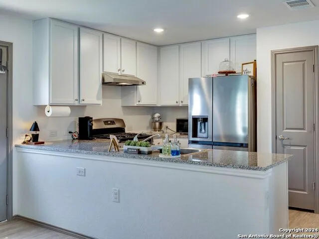 a kitchen with stainless steel appliances granite countertop a refrigerator sink and cabinets