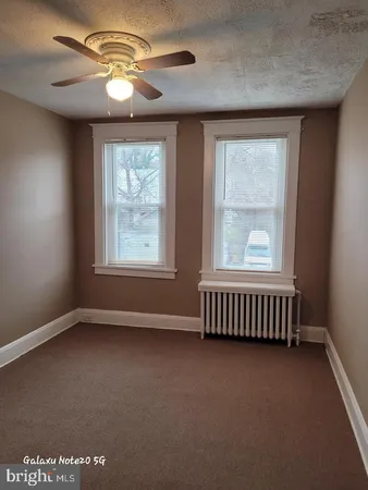 an empty room with windows and chandelier fan