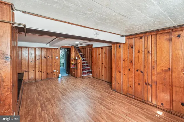 a view of an empty room with wooden floor and furniture