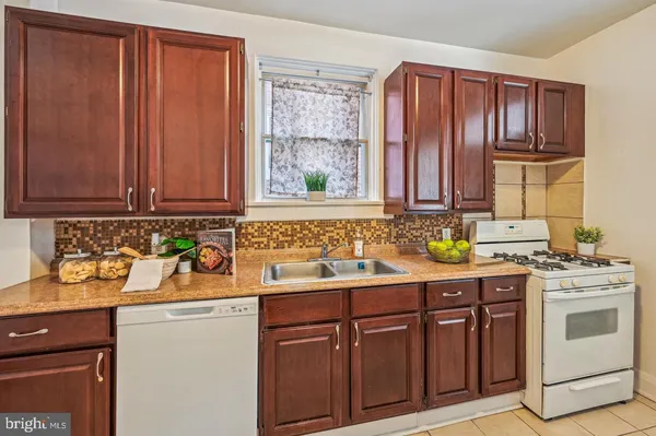 a kitchen with stainless steel appliances granite countertop wooden cabinets a sink a stove a chimney and a counter space