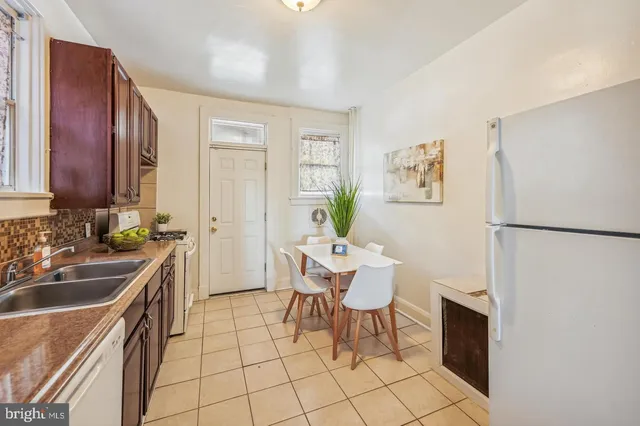 a kitchen with a sink chairs and refrigerator
