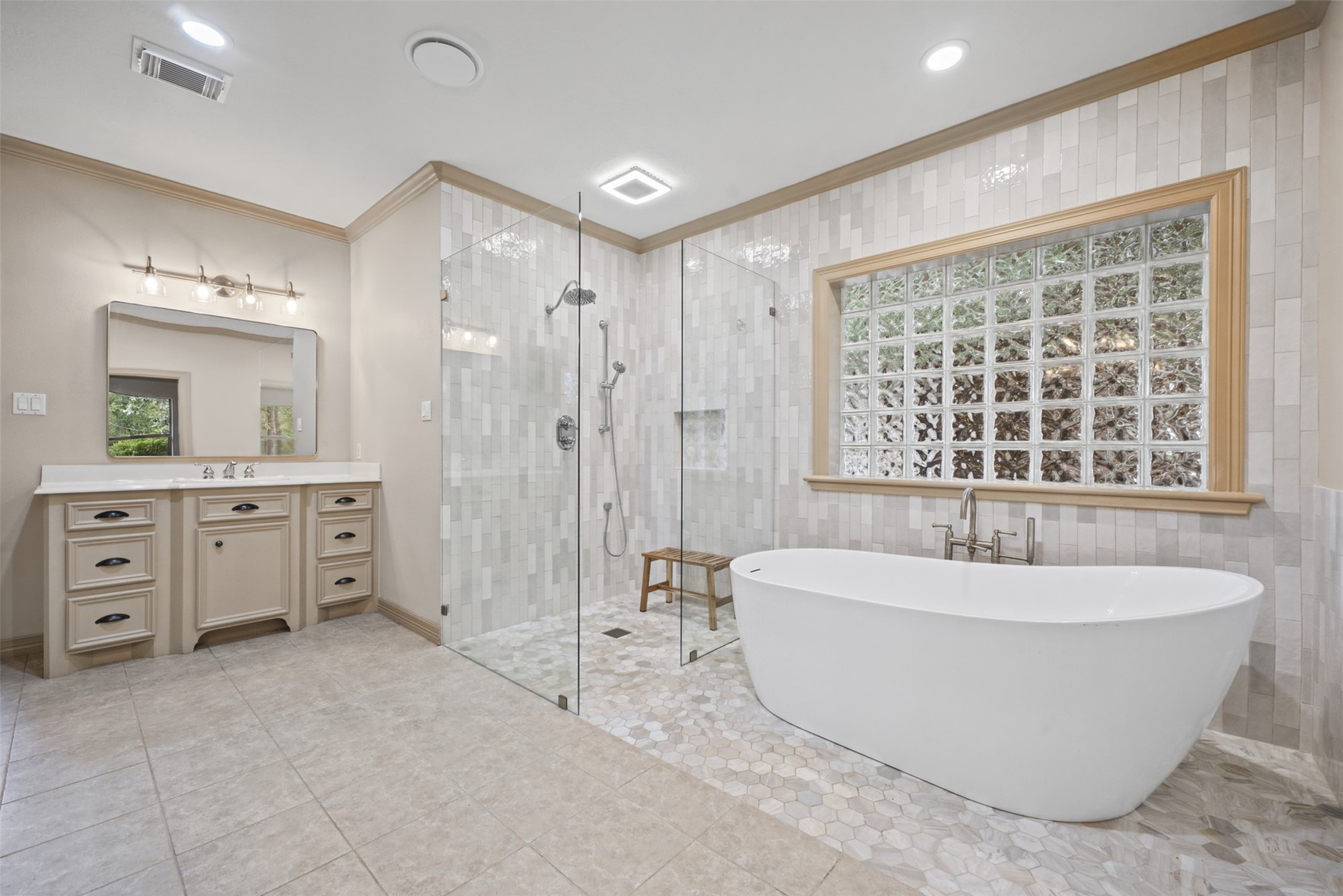 25119 Arcane Court Spring, TX 77389 - Photo 22 of 50 Recently Remodeled with Style & Function in Mind! The primary bath showcases tile flooring, crown molding, recessed lighting, and dual vanities, along with a spacious walk-in shower and striking freestanding vessel soaking tub. A large privacy-glass window fills the room with natural light, while thoughtful details include a private commode with bidet, linen cabinetry with a built-in laundry hamper, and convenient direct access to the laundry room.