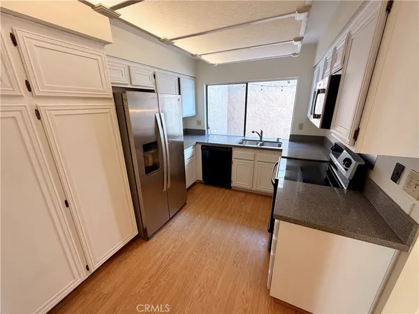 a kitchen with stainless steel appliances granite countertop a refrigerator a sink a stove a washer dryer and a refrigerator