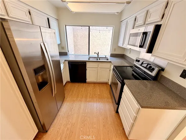 a kitchen with granite countertop a refrigerator a sink a stove a washer dryer and a refrigerator