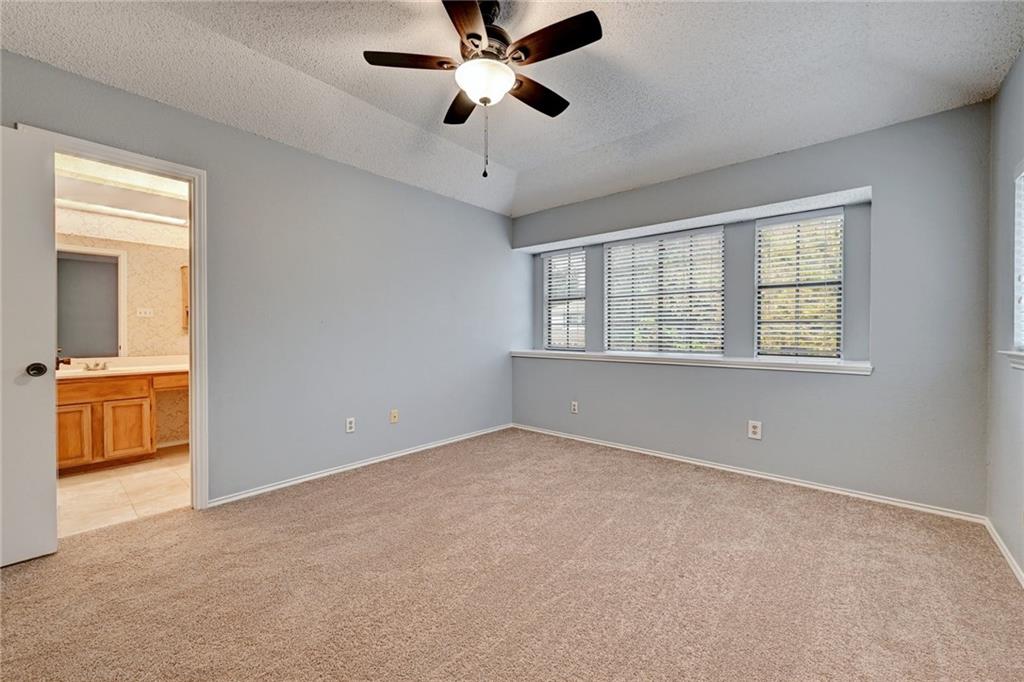 12915 Modena Trail Austin, TX 78729 - Photo 13 of 16 A spacious bedroom features soft carpeting, high ceilings, and integrated private bathroom access.