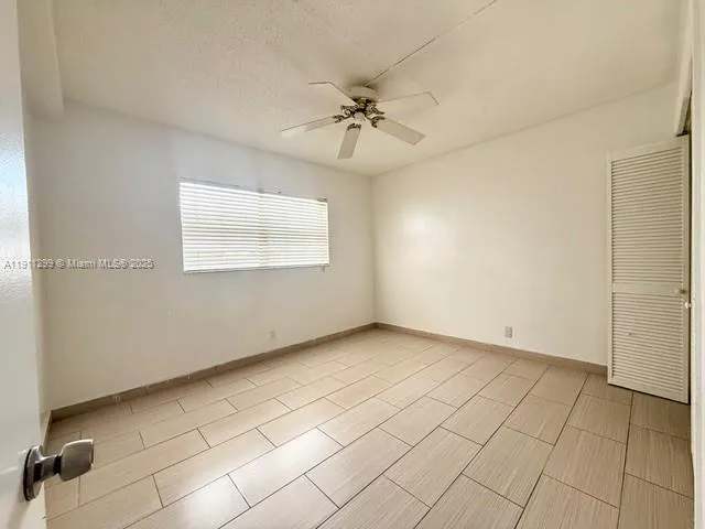 an empty room with windows and ceiling fan