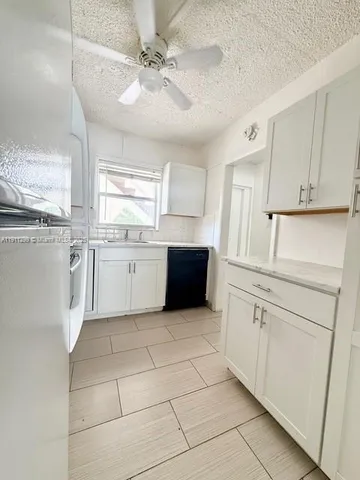 a kitchen with granite countertop white cabinets and white appliances