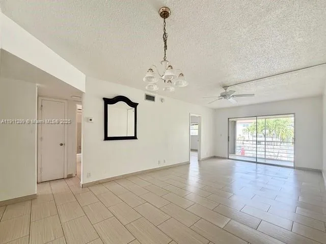 an empty room with chandelier and windows