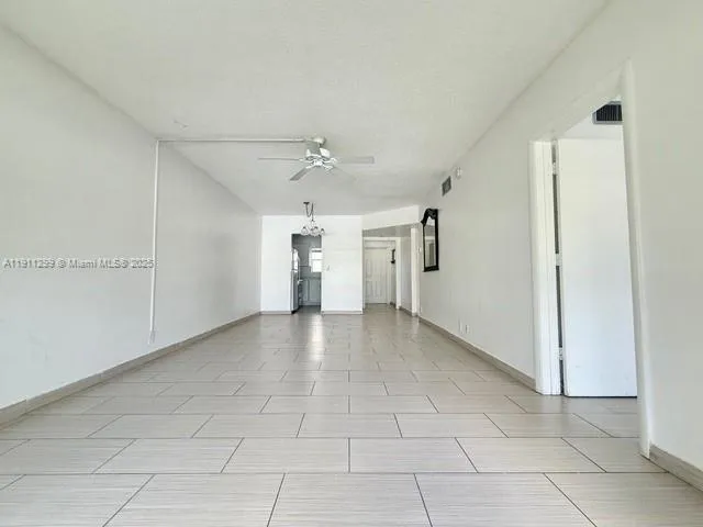 a view of a livingroom with a chandelier fan and windows