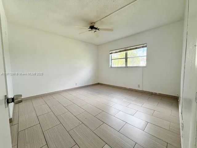 an empty room with a ceiling fan and a window