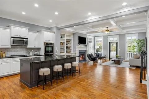 a living room with couches and kitchen view with wooden floor
