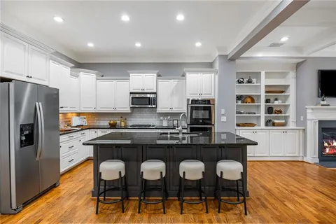 a kitchen with stainless steel appliances granite countertop a table chairs refrigerator and cabinets