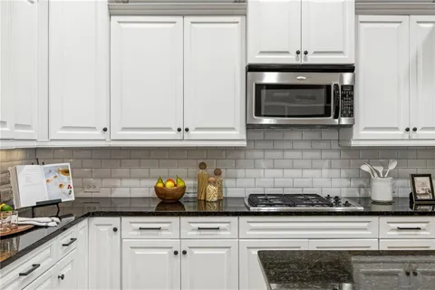 a kitchen with stainless steel appliances granite countertop white cabinets and a stove a oven with white countertops