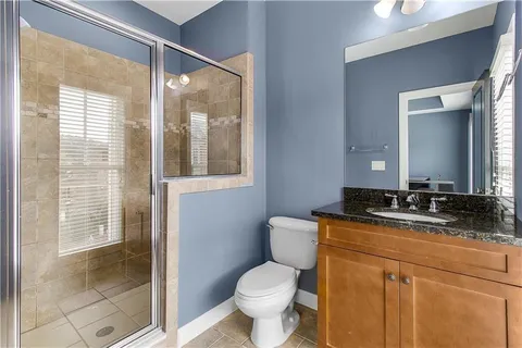 a bathroom with a granite countertop toilet a sink and a mirror
