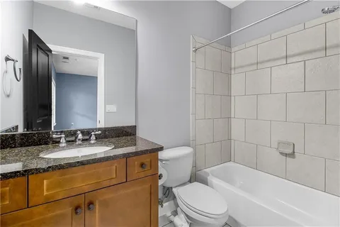 a bathroom with a granite countertop sink toilet mirror and bathtub