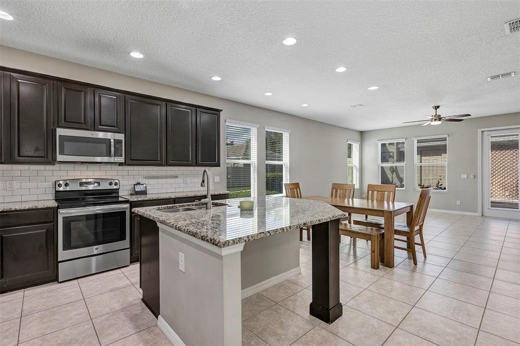 7644 Ripplepointe Way Windermere, FL 34786 - Photo 3 of 52 a kitchen with stainless steel appliances granite countertop a stove top oven a sink dishwasher a dining table and chairs with wooden floor