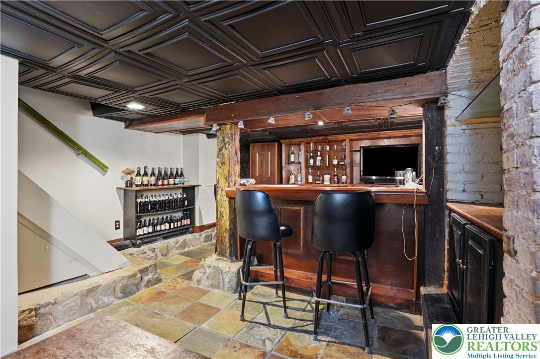 2014 Linden Street Bethlehem, PA 18017 - Photo 51 of 85 A well-appointed wet bar area features exposed wood beams, brickwork, and a tiled floor, creating a rustic yet refined atmosphere.